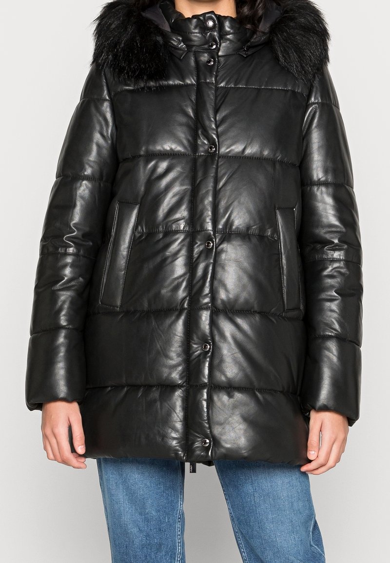 Černá kožená péřová bunda s kožešinovou kapucí, zapínáním na knoflíky a dvěma bočními kapsami. Design zahrnuje prošívané panely pro zvýšení textury.