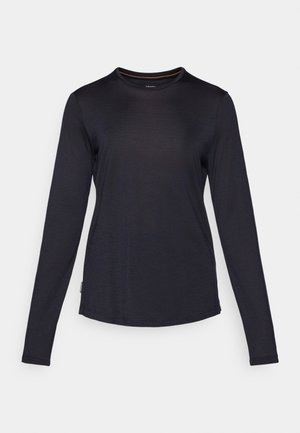 Long-sleeve shirt in navy blue, made of soft material with a crew neck, subtle texture, and curved hem. Features a small logo tag.