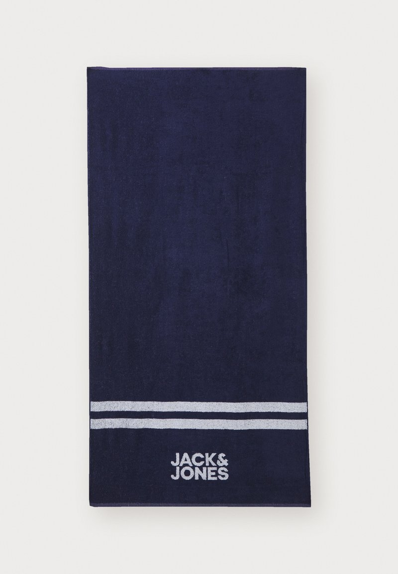 Serviette de bain marine en coton doux, ornée de deux rayures blanches et d'un logo brodé "JACK & JONES" près du bas. Forme rectangulaire.
