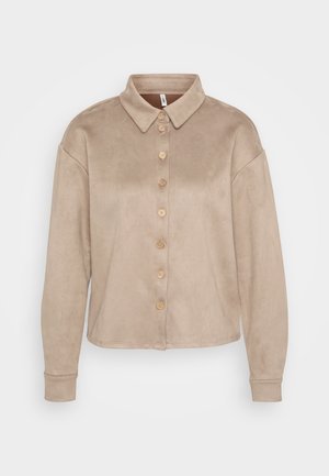 Chemise beige à boutonnage avant en matériau doux semblable au daim. Elle présente un col, des manches longues et des boutons en bois sur le devant.
