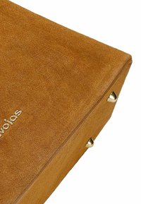 Brązowa zamszowa prostokątna torba o teksturowanym wykończeniu, z złotymi metalowymi akcentami na rogach i logo wytłoczonym na powierzchni.