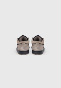 Ζευγάρι γκρι και μαύρα παπούτσια Air Jordan, εμφανιζόμενα από πίσω με το λογότυπο στη φτέρνα, σε απλό λευκό φόντο.