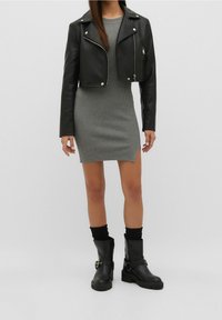Czarna, krótka skórzana kurtka z srebrnymi zamkami, połączona z szarym, prążkowanym sukienką oraz czarnymi botkami za kostkę z klamrami i teksturowanymi podeszwami.
