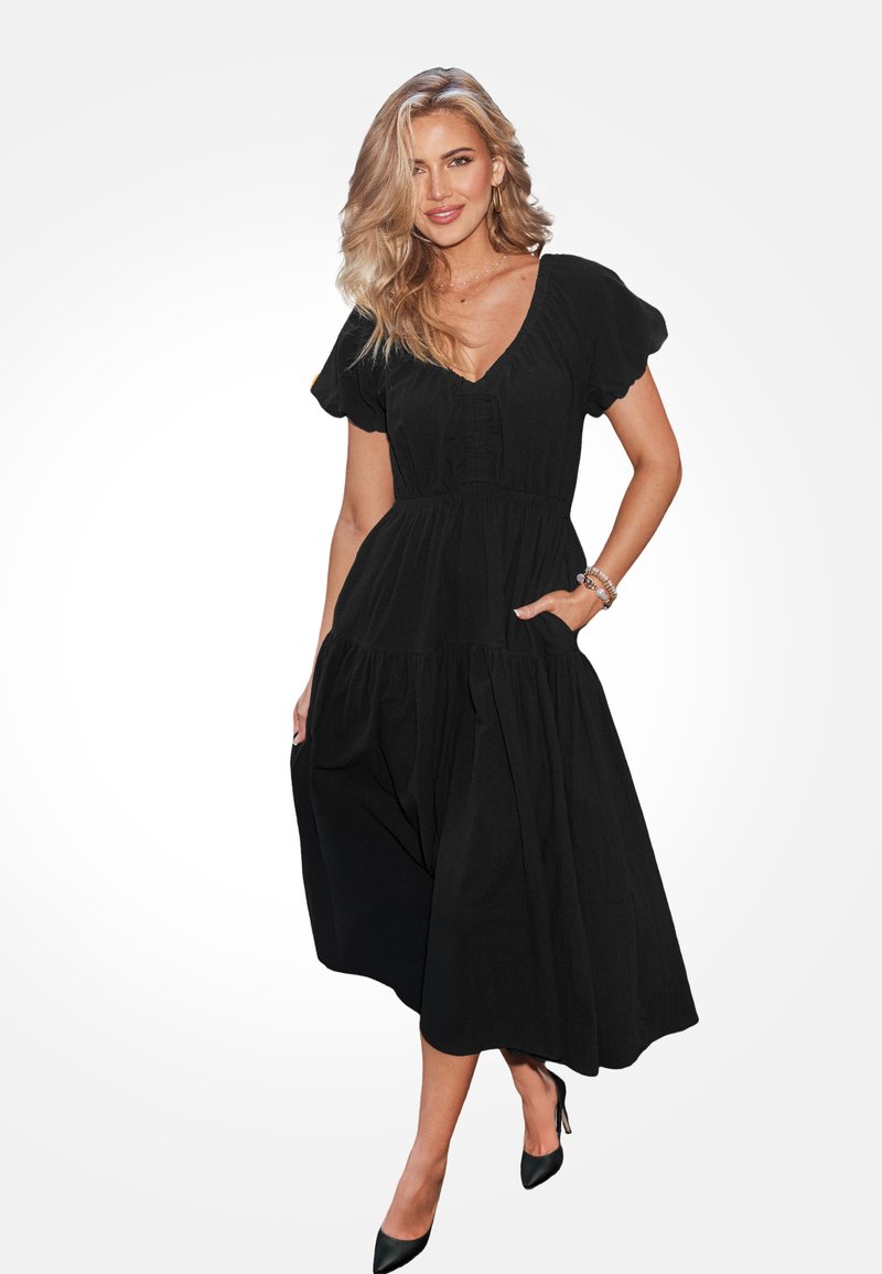 Czarna sukienka z krótkim rękawem i dekoltem w kształcie V, zebranym korpusem i płynącą, warstwową spódnicą. Posiada kieszenie i fakturowany detal z przodu.