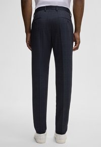 Dunkelblaue gemusterte Hosen mit einer strukturierten Oberfläche, geradem Schnitt, seitlichen Taschen und einem Gürtelschlaufen an der Taille.