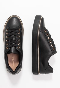 Black leather sneakers with a textured finish, featuring rose gold eyelets, black laces, and a rubber sole with a contrasting edge.