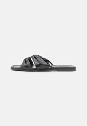 Sort flad slip-in sandal med to brede snoede læderremme over toppen og et firkantet tådesign på hvid baggrund.