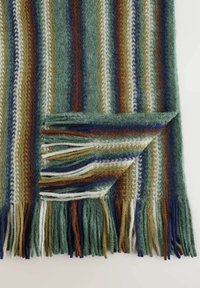 Coperta lavorata a maglia con strisce verdi, marroni e crema. Rifinita con bordi frangiati e una superficie morbida e testurizzata.