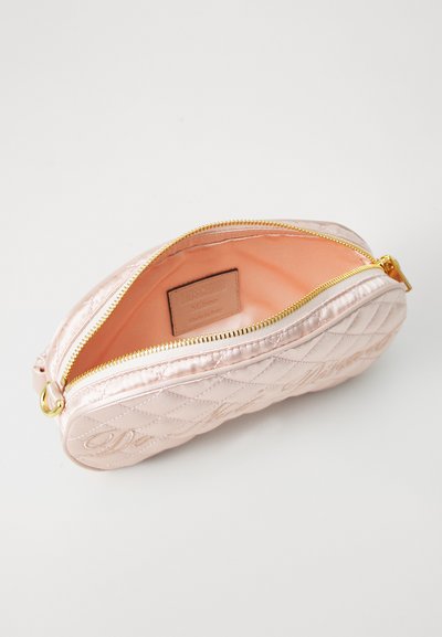 Kviltad rosa satinhandske med gulddragkedja, med öppen topp och orangefärgad foder, som visar en varumärkesetikett inuti.