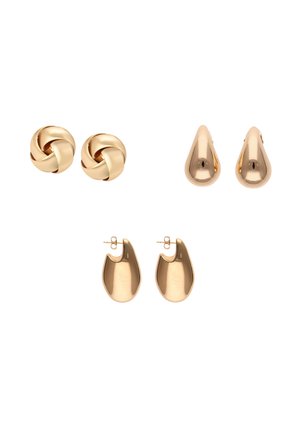 Trzy pary złotych kolczyków na sztyft: skręcony supeł, gładka łezka oraz zakrzywiony abstrakcyjny kształt na białym tle.