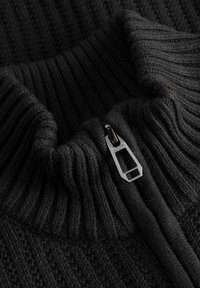 Schwarzer Strickpullover mit gerippter Struktur, hohem Kragen und einem Metallreißverschluss. Verfügt über ein dezentes Muster und eine weiche Stoffoberfläche.