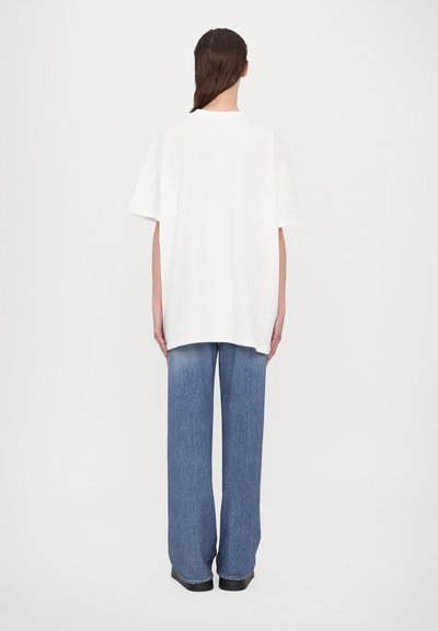 White oversized t-shirt with short sleeves, paired with wide-leg faded blue jeans. Simple design, soft texture, and casual fit.