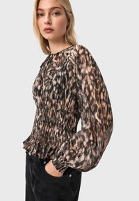 Μπλούζα με λεοπάρ σχέδιο από ελαφρύ ύφασμα. Διαθέτει φουσκωτά μανίκια, ελαστική μέση και πιέτες στον καρπό. Κυριαρχούν οι γήινες αποχρώσεις στο σχέδιο.