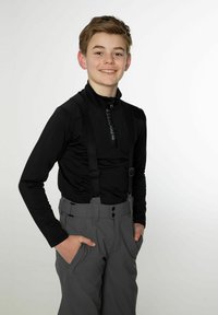 Crna majica dugih rukava sa zipom u kombinaciji sivo-skih hlača s podesivim trakama, džepovima i detaljima s gumbima. Glatke teksture.