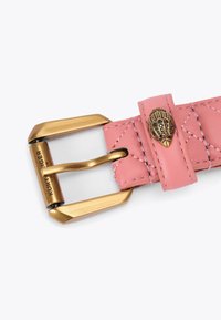 Cintura in pelle rosa con texture trapuntata, dotata di una fibbia in metallo dorato e un accento a forma di conchiglia con decorazioni nere.