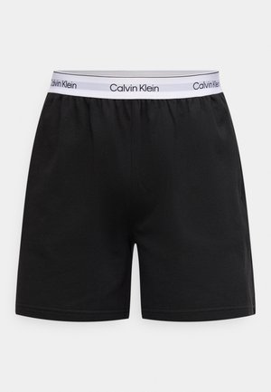 Czarne bawełniane szorty z elastycznym pasem, na którym znajduje się biały logo Calvin Klein. Prosty, prosty krój bez wzorów.