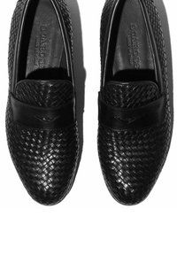 Crne kožne cipele na slip-on s tkanim teksturom na prednjem dijelu i glatkom kožnom trakom preko gornjeg dijela stopala. Unutrašnjost sadrži detalj s logotipom.