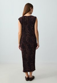 Zwart en bruin gestreepte mouwloze maxi-jurk met een geplooide textuur, voorzien van een ronde halslijn en een rechte silhouette.