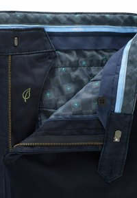 Navy blue pants with a smooth texture, featuring a gold zipper, patterned inner lining in blue and gray, and a leaf logo in green.