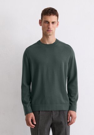 Ciemnozielony sweter crewneck wykonany z gładkiego materiału. Posiada długie rękawy, ściągacze na końcach rękawów oraz dopasowany dół. Minimalistyczny design bez ozdób.