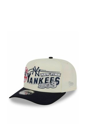 Weißer und schwarzer New York Yankees-Basecap mit gesticktem Teamnamen, Logo und "1903" auf der Vorderseite, aus einem schrägen Seitenwinkel gezeigt.