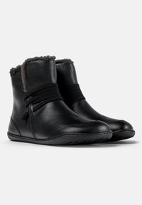 Bottines en cuir noir avec une doublure en fourrure grise douce en haut, dotées de bandes élastiques pour la fermeture et d'une semelle souple.