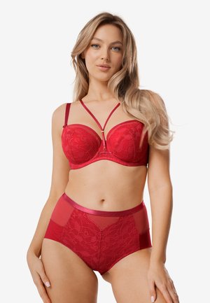 Czerwony koronkowy biustonosz z siateczkowymi detalami i złotymi elementami ozdobnymi, połączony z czerwonymi majtkami z wysokim stanem, ozdobionymi koronką i przezroczystymi panelami.