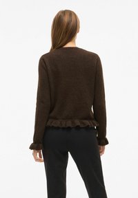 Brūns strukturēts adīts džemperis ar kroku akcentiem ap apakšmalu un piedurknēm, ar klasisku apaļu kakla izgriezumu un brīvu piegriezumu.