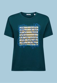 Mörkblågrön kortärmad T-shirt med ett fyrkantigt mönster på framsidan av beige och vita ränder, överlagda med skisser av blommor i blått.