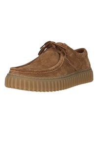 Chaussure décontractée en suède marron à lacets, avec une semelle en caoutchouc épaisse à rainures et des détails cousus sur la tige.