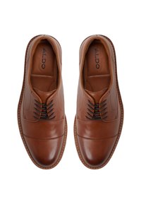 Zapatos de cuero marrón con una textura suave, con puntera redondeada, cordones decorativos y un sutil patrón de costura a lo largo de los bordes.