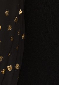 Tissu noir avec des petites taches de feuille d'or texturées dispersées sur le côté gauche et une texture tricotée noire unie sur le côté droit.