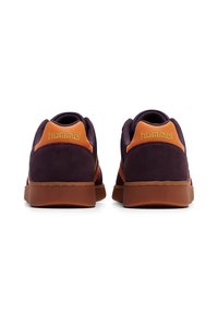 Ett par lila och orange Hummel sneakers som visas bakifrån på en vit bakgrund.