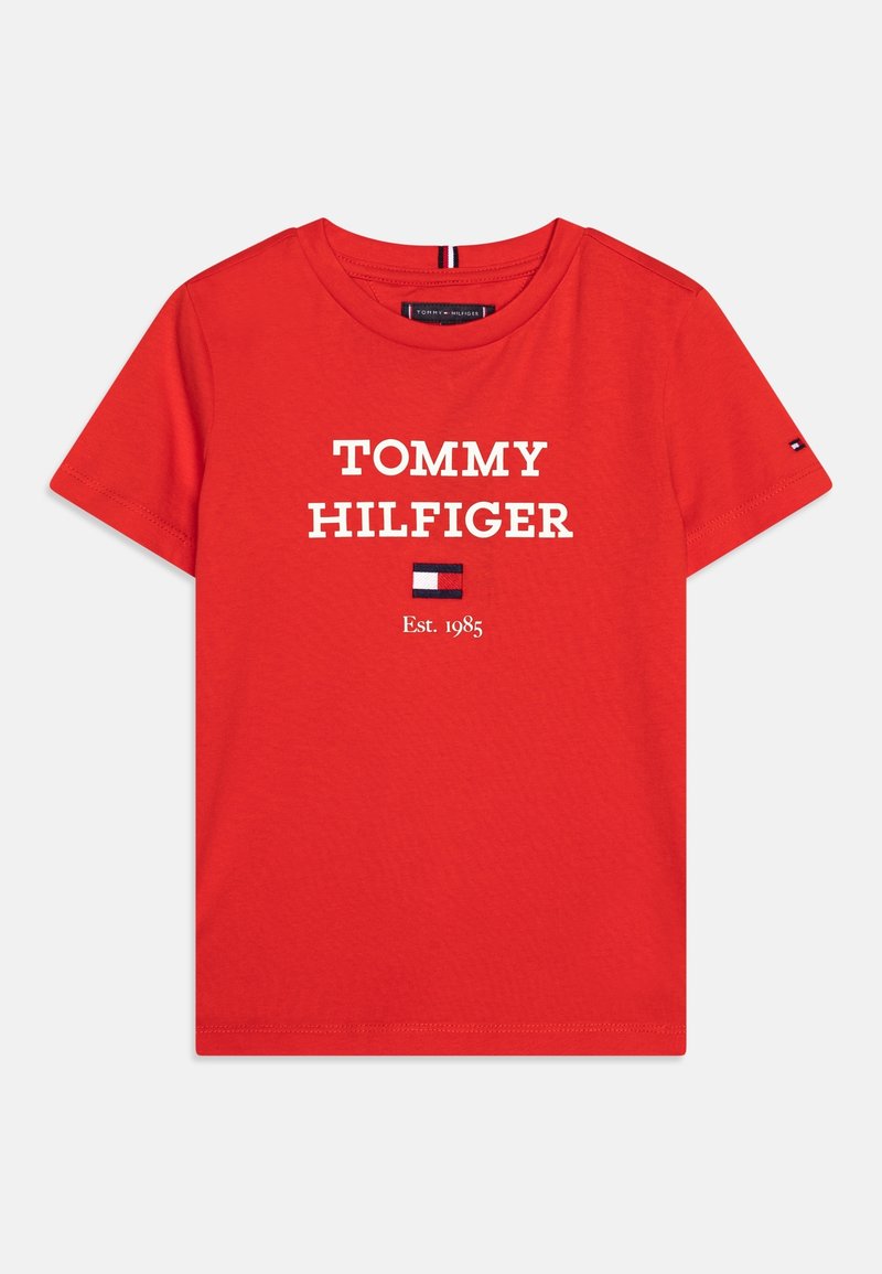T-shirt rouge à manches courtes avec texte « "Tommy Hilfiger" », petit logo drapeau et "Est. 1985" imprimé en blanc sur le devant.
