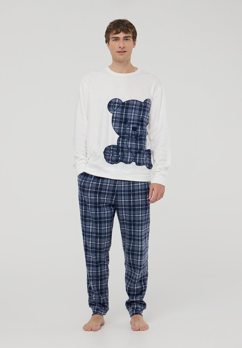 Biała koszula z długim rękawem z nadrukiem niedźwiedzia w granatową kratę, w zestawie z granatowymi spodniami piżamowymi w kratę. Miękka tkanina o luźnym kroju.