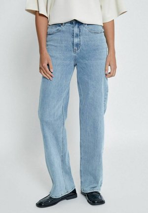 Jeans a vita alta in denim di colore azzurro chiaro, con gamba larga e classico design a cinque tasche. Indossati con scarpe nere.