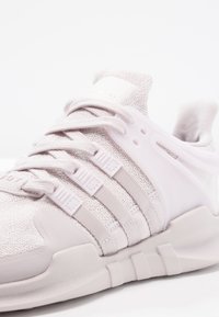 Ljusrosa träningsskor gjorda av texturerat nätmaterial med gummidetaljer, med tre ränder design och en dämpad sula.