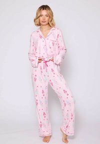 Conjunto de pijama rosa con mangas largas y pantalones, que presenta un patrón juguetón de cascanueces y corazones. Tejido ligero y suave con un corte holgado.