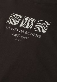 Sort stof med tre hvide abstrakte zebra striber over teksten "LA VITA DA BOHÈME caffè capri ITALY."