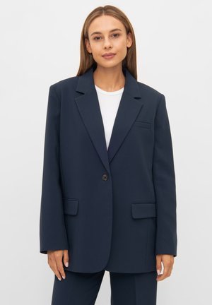 Blazer blu scuro con spalle strutturate, chiusura a un bottone e due tasche frontali. Realizzato in tessuto liscio con un design su misura.
