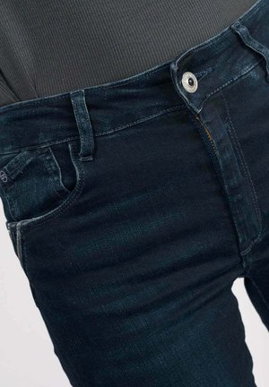 Donkerblauwe denim jeans met een slim fit, vijf zakken en een zilveren knop aan de tailleband. Gelaagd stof met lichte vervaging.