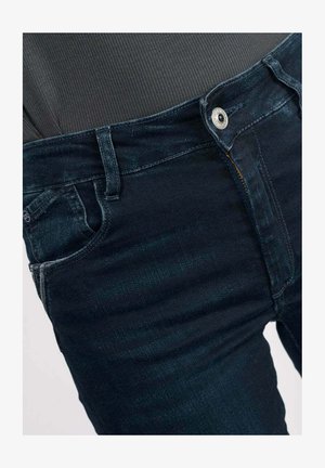 Donkerblauwe denim jeans met een slim fit, vijf zakken en een zilveren knop aan de tailleband. Gelaagd stof met lichte vervaging.