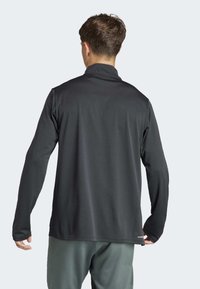 Schwarze Pulloverjacke mit langen Ärmeln, hohem Kragen und glatter Textur, mit geradem Saum und minimaler Branding auf der Rückseite.