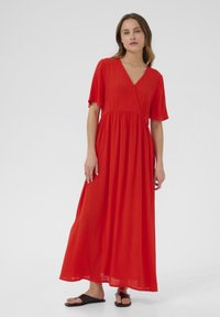 Robe maxi rouge avec un décolleté en V, des manches courtes à volants et une taille cintrée, fabriquée en tissu léger avec une texture subtile.