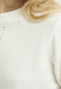 Maglione lavorato a maglia in morbida lana bianca, con collo rotondo a costine e un elegante motivo testurizzato, dal taglio rilassato e tessuto avvolgente.