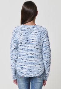 Pullover blu chiaro in un tessuto morbido e testurizzato con una fantasia a righe di accenti blu scuro. Presenta maniche lunghe e un orlo arrotondato.