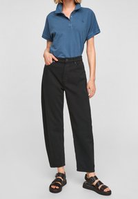 Pánská polokošile modré barvy z bavlny s límečkem a třemi knoflíky; v kombinaci s černými kalhotami s vysokým pasem a černými sandály se sponami.