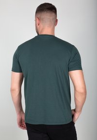 Dunkelgrünes T-Shirt mit kurzen Ärmeln, glatte Textur, runder Ausschnitt und schlichtes Design. Die Rückansicht zeigt die Passform von Schulter und Ärmeln.