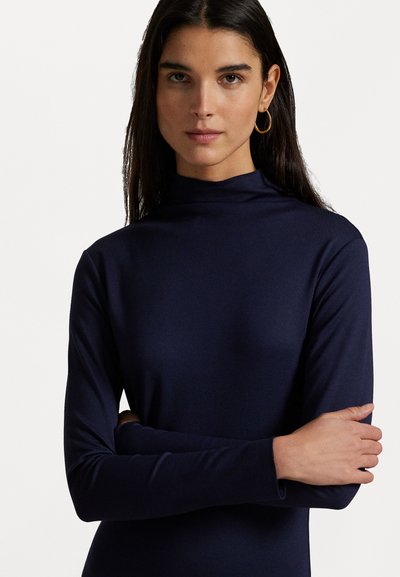 Top de cuello alto de manga larga en color azul marino, con una textura suave y elástica. Presenta un escote alto y una silueta ajustada.