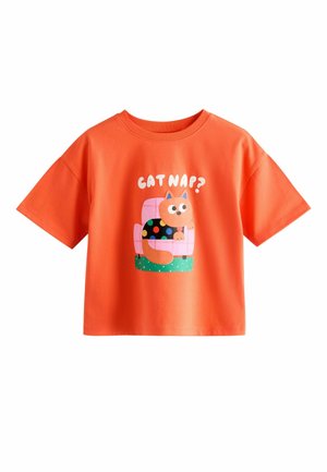 Orange short-sleeve shirt with a cartoon cat wearing a black polka-dot sweater sitting on a pink chair and text "CAT NAP?" above.
